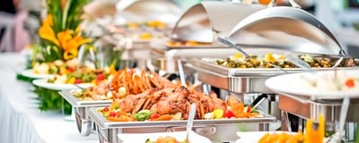 Auf dem Bild ist ein Buffet mit verschiedenen Speisen in Wärmeschalen präsentiert.